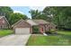 Beautiful brick home with a well-manicured lawn, landscaped garden beds, and a inviting red front door at 14747 Pomerol Ln, Pineville, NC 28134