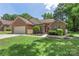 Beautifully landscaped brick home with an attached two car garage, lush lawn, and a cheerful red front door at 14747 Pomerol Ln, Pineville, NC 28134