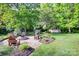 Beautiful backyard featuring a fire pit and chairs surrounded by lush landscaping and mature trees at 1498 Legion Rd, Fort Mill, SC 29715