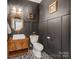 Stylish powder room with dark walls, wainscoting, patterned tile floor, and decorative mirror at 1605 Ambergate Dr, Waxhaw, NC 28173