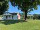 White one-story home with a brick chimney, carport, and a large tree in the front yard at 22987 Alonzo Rd, Oakboro, NC 28129