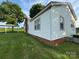 A side view of the home with white siding, brick foundation, and shaded carport at 22987 Alonzo Rd, Oakboro, NC 28129