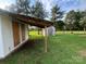Exterior side view featuring covered structure, boarded windows, and ample backyard space at 22987 Alonzo Rd, Oakboro, NC 28129