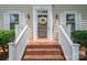 Close-up of the front door with brick steps, trimmed in white rails, a decorative wreath, and sidelight windows at 2410 Monticello Dr, Gastonia, NC 28056