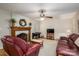 Comfortable living room with hardwood floors, brick fireplace, vintage wood mantle, and two plush maroon sofas at 2410 Monticello Dr, Gastonia, NC 28056