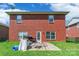 Back exterior view of a red brick home with a door leading to a patio and a grassy backyard at 2476 Glyncastle Way, Gastonia, NC 28056