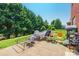 A spacious backyard with a patio, green lawn, mature trees, and a red brick house at 2476 Glyncastle Way, Gastonia, NC 28056