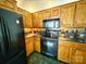 This kitchen is equipped with modern black appliances, wooden cabinets, and green-tiled flooring at 2511 Old Pond Dr, Lincolnton, NC 28092