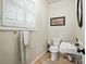 Cozy half bathroom with a pedestal sink, toilet, and framed artwork, illuminated by a window with white shutters at 307 Dogwood Dr, Mount Holly, NC 28120