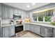 Kitchen with gray cabinets, stainless steel appliances, corner sink, and brick floors at 307 Dogwood Dr, Mount Holly, NC 28120