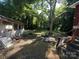 Overgrown backyard with mature tree, dilapidated house and covered structure and discarded construction materials at 310 E Division Ave, East Spencer, NC 28039