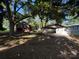 Dilapidated home with brick and wood and a covered shelter with overgrown yard and mature trees at 310 E Division Ave, East Spencer, NC 28039