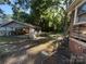 View of a dilapidated home with covered shelter, overgrown yard and scattered construction materials at 310 E Division Ave, East Spencer, NC 28039