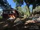 View of the back of a brick home with mature trees in the yard and a covered shelter in the background at 310 E Division Ave, East Spencer, NC 28039