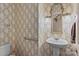 Cozy half-bathroom featuring a pedestal sink, classic wallpaper, and decorative mirror at 322 Oakview Dr, Salisbury, NC 28146