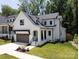 New construction home with a modern farmhouse style, gray garage, and well manicured lawn at 3953 Plainview Rd, Charlotte, NC 28208