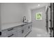 Laundry room features light blue shaker cabinets, modern black hardware, window and sleek countertops at 3953 Plainview Rd, Charlotte, NC 28208