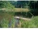 A pond with a small wooden dock and chair, surrounded by lush greenery at 404 Long Shoals Rd, Bessemer City, NC 28016