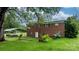 View of the brick home's backyard with a covered structure, complemented by lush greenery and landscaping at 5083 Fleetwood Dr, Hickory, NC 28602