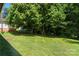View of backyard with a lush green lawn, mature trees, and partial view of home at 517 Dutch Ave, Mount Holly, NC 28120