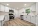 Modern kitchen featuring white cabinets, stainless steel appliances, and wood-look floors, and natural light at 517 Dutch Ave, Mount Holly, NC 28120