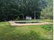 Backyard view of an in-ground pool surrounded by a lush green lawn and mature trees at 5324 Weblee Ct, Kings Mountain, NC 28086