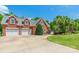 Classic brick home featuring a three-car garage and a well-manicured lawn with mature palm trees at 572 W Shiloh Unity Rd, Lancaster, SC 29720