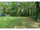 A large grassy backyard surrounded by mature trees offers a tranquil and private outdoor space to enjoy at 5914 Mt Holly Huntersville Rd, Charlotte, NC 28216