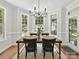 Sunlit dining room featuring rustic wood table, updated chandelier, and large windows overlooking the landscaped yard at 5955 Mountain Point Ln, Charlotte, NC 28216