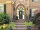 Charming brick home entrance, featuring a stone archway, manicured landscaping, and wrought iron railings at 5955 Mountain Point Ln, Charlotte, NC 28216