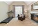 Bright living room featuring a cozy fireplace, armchair, and treadmill for a balanced living space at 5955 Mountain Point Ln, Charlotte, NC 28216