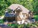 Aerial view of the rear exterior showcasing a large brick home with covered and uncovered patios at 5955 Mountain Point Ln, Charlotte, NC 28216