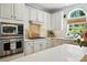 Well-lit kitchen with stainless steel appliances, white cabinets, tile backsplash, and a kitchen sink overlooking the yard at 606 Vega Nw St, Concord, NC 28027