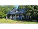Two-story home with damaged facade, covered front porch, and blue front door at 619 N Main St, Landis, NC 28088