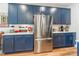 Spacious kitchen featuring stainless steel refrigerator and sleek, blue cabinetry with gold hardware at 8516 Profit Ln, Charlotte, NC 28215