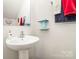 Compact half bathroom with pedestal sink, mirror, and minimalist decor at 9807 Maywine Cir, Huntersville, NC 28078