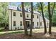 Beautiful white brick two-story home with black trim and roof nestled among mature trees at 9830 Spring Harvest Dr, Mint Hill, NC 28227