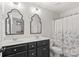Bathroom with double sinks, dark cabinets, framed mirrors, a shower/tub combo and floral shower curtain at 1011 Wadsworth Ln, Indian Trail, NC 28079