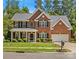 Elegant two-story brick home with a manicured lawn, mature trees, and a two-car garage at 1011 Wadsworth Ln, Indian Trail, NC 28079