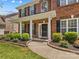 Inviting front porch and entrance with professional landscaping featuring lush plants and classic brick and black color scheme at 1011 Wadsworth Ln, Indian Trail, NC 28079