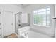 Bathroom boasting a glass shower, tub, white walls, and a decorative privacy glass block window at 10509 Serape Rd, Charlotte, NC 28277