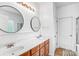 Bathroom with double sinks, wooden cabinets, and round mirrors above a long white countertop at 10509 Serape Rd, Charlotte, NC 28277