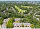 Aerial view of residences surrounded by lush trees, near green golf course, and with skyline in distance at 11021 Dundarrach Ln # 40, Charlotte, NC 28277