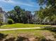 View of green community lawn lined with mature shade trees and townhomes in the background at 11021 Dundarrach Ln # 40, Charlotte, NC 28277