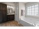Bright bathroom features a soaking tub, dark wood vanity, and a large window providing natural light at 112 Steeplechase Ave, Mooresville, NC 28117