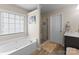 Bright bathroom features a soaking tub and glass shower, with a marble-topped vanity, and wood-look tile flooring at 112 Steeplechase Ave, Mooresville, NC 28117