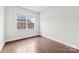 A serene bedroom with gleaming hardwood floors and a window view of a charming exterior facade at 1300 Dali Blvd, Mount Holly, NC 28120