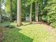 Large backyard with mature trees and lawn, featuring a small storage shed nestled among the trees at 13037 Angel Oak Dr, Huntersville, NC 28078