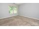 Empty bedroom showcasing a large window with wooded view and neutral carpet at 13037 Angel Oak Dr, Huntersville, NC 28078