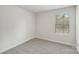 Minimalist bedroom featuring neutral carpet, white walls, single window, and essential electrical outlets at 135 Utility Ln # E, Mooresville, NC 28117